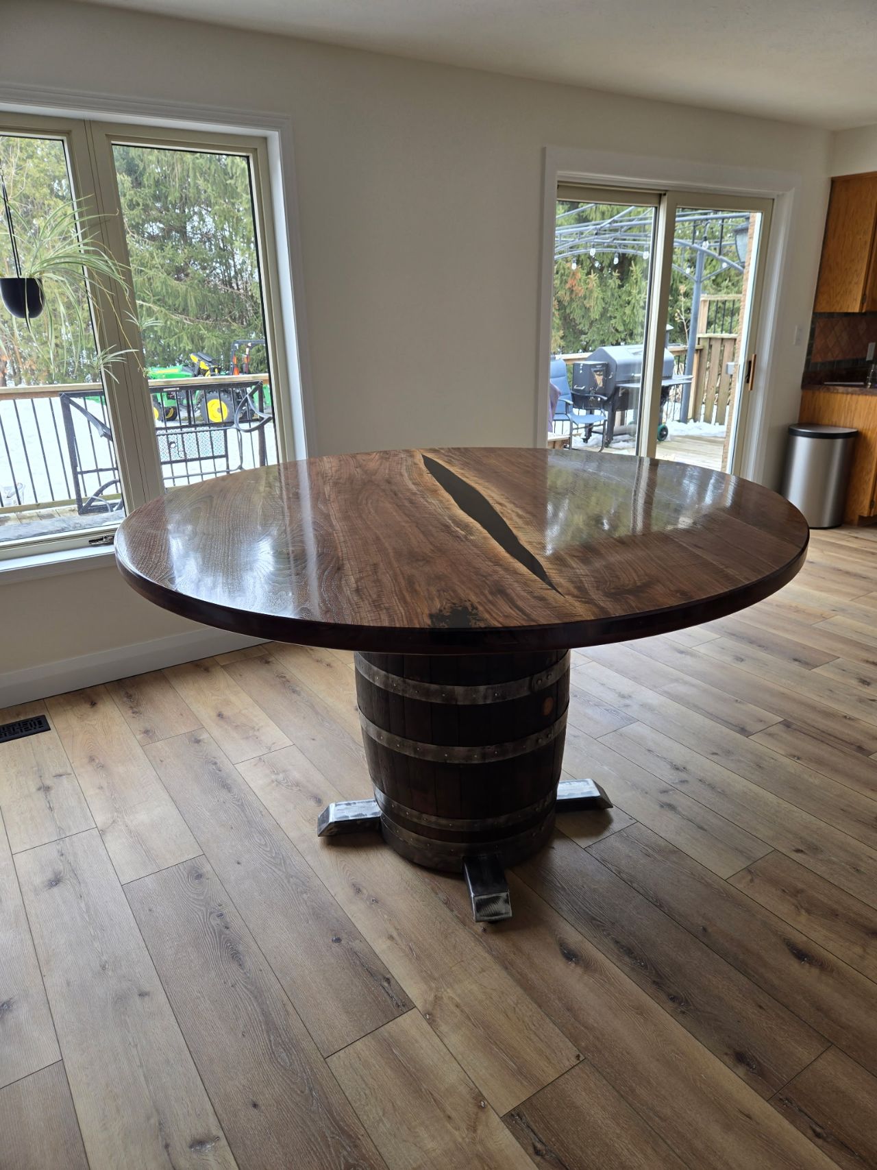 Round black walnut dining table on a reclaimed whiskey-barrel pedestal